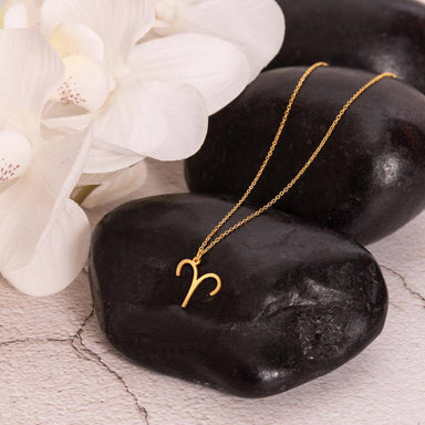 18k yellow gold Aries zodiac sign necklaces showcase on rock