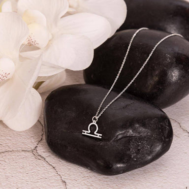 polished stainless steel Libra zodiac sign necklaces showcase on rock